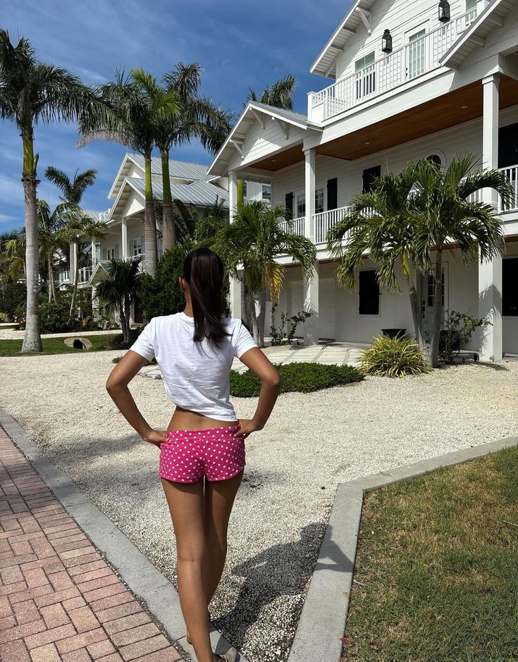 Woman standing in front of a large house with palm trees