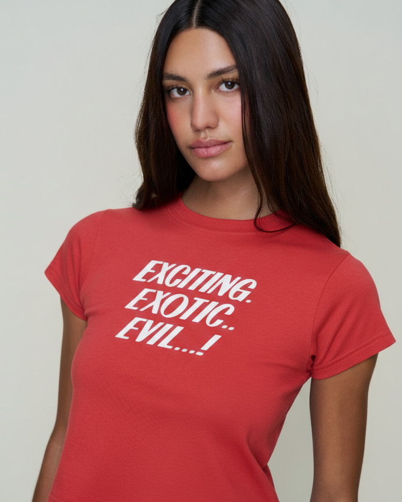 Person wearing a red y2k baby tee with words"exciting, exotic, evil" white text on a plain background