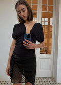 Woman taking a mirror selfie wearing a black outfit with sheer details.