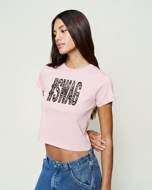 Woman wearing a pink t-shirt with text, standing against a plain background