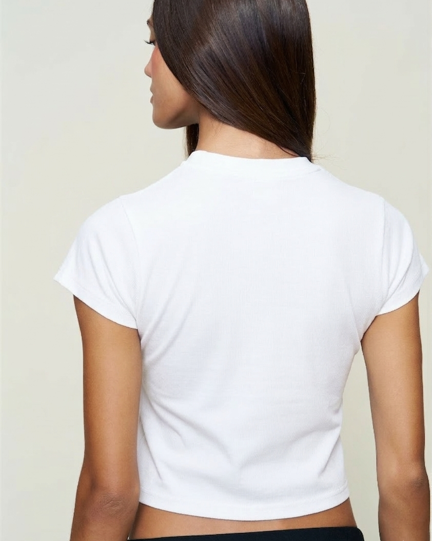 Person wearing a white crop top against a plain background