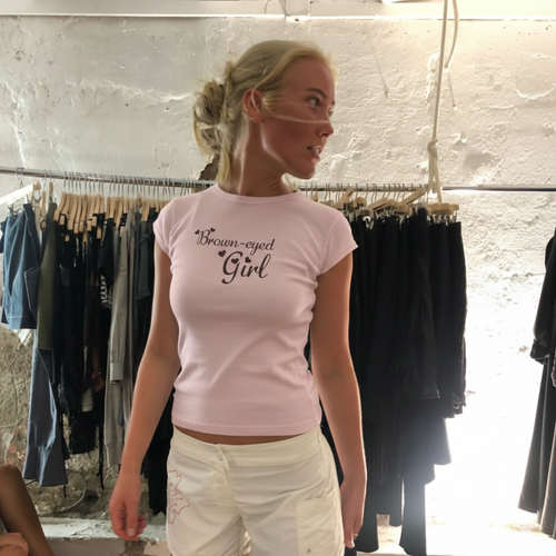 Woman wearing a pink t-shirt with text in a clothing store.
