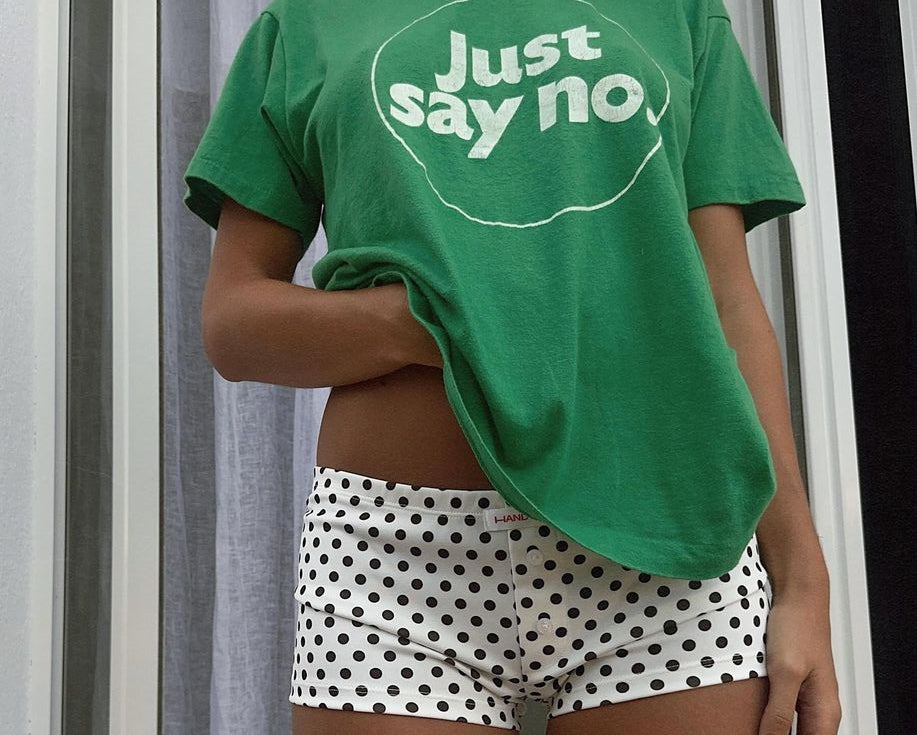 Person wearing a green t-shirt with 'Just say no' text and polka dot shorts.