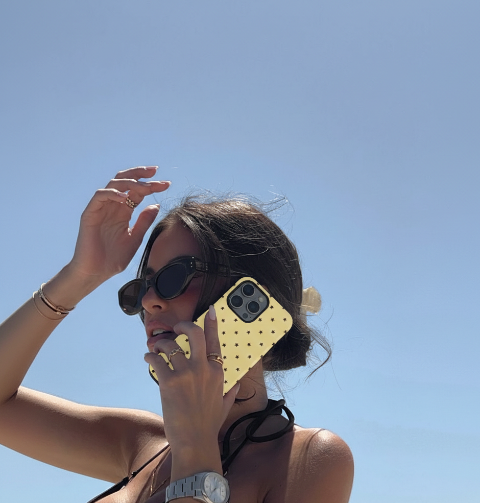 Woman holding a phone with a yellow case against a clear blue sky